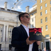man with red preserved roses in black box